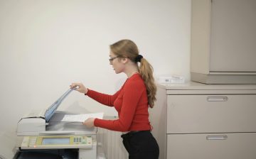 An office employee using a photocopier to copy documents indoors.
